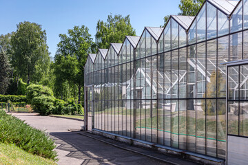 Obraz premium greenhouse in the botanical garden on sunny summer day in an environment of green trees