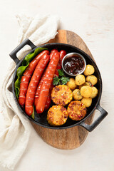 Grilled meat sausages in a pan with vegetables.
