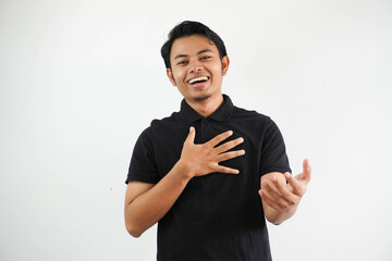 young asian man smiling friendly and doing welcoming pose with hands pressed to the chest and open arms wearing black polo t shirt isolated on white background