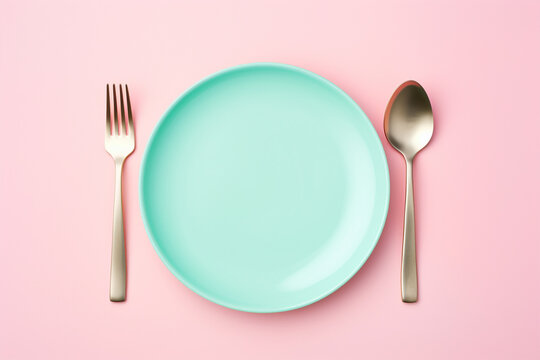 Empty plate with fork and spoon on pink background