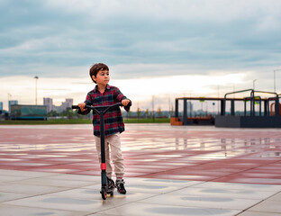 Obraz premium Little boy riding a scooter at the stadium in the evening.