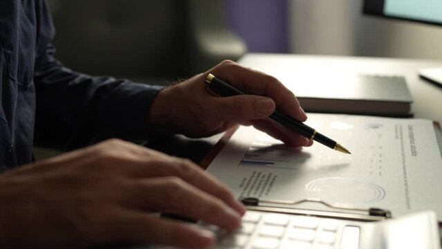 Asian businessman working in the office, calculating financial reports, organizing paperwork using a laptop and calculator as an aid. management concept accounting.
