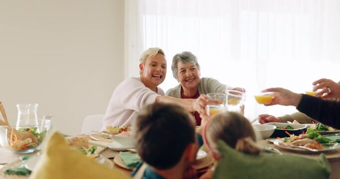 Family, lunch and juice toast in dining room with love, bonding and conversation at home. Food, cheers and children with grandparents, parents and orange fruit drink for brunch, meal or celebration