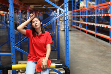 Portrait of warehouse workers young asian woman sitting and taking a break while wipe the sweat...