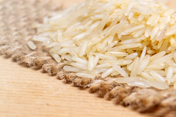 Rice on top of a jute fabric on wood surface