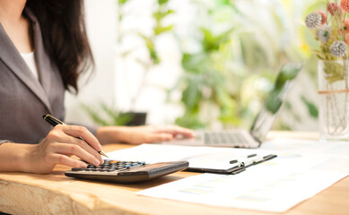 Asian businesswoman sit at their desks and calculate financial graphs showing results about their investments, plan a successful business growth process