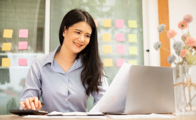 Asian businesswoman sit at their desks and calculate financial graphs showing results about their...