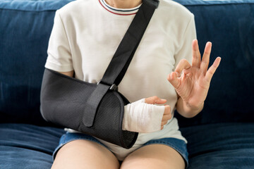 Social security and health insurance concept. Young woman suffer pain from accident fracture broken bone injury with arms splints in cast sling support arm in living room.