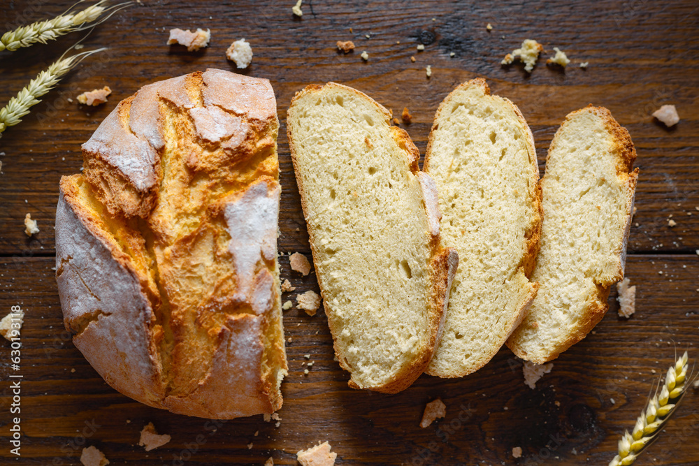 Aufkleber loaf of sliced bread with crumbs and ears of wheat on wooden table close up