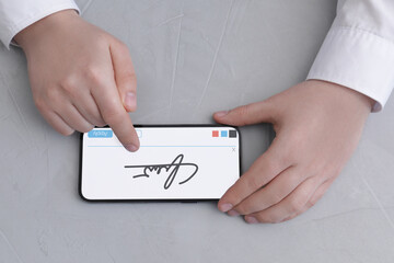 Electronic signature. Man using mobile phone at grey table, top view
