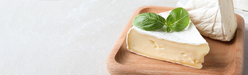 Tasty brie cheese on light table, closeup. Banner design with space for text