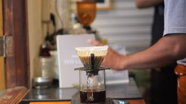 An Indonesian baristasa preparing Drip Brew Coffee. Alternative coffee brewing method, using pour over dripper and paper filter.