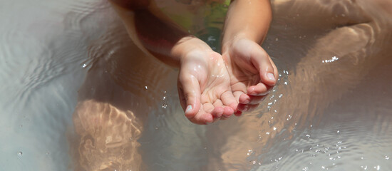 Fototapeta premium Baby hands in the water in the inflatable pool.