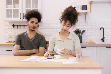 man and woman couple pay electricity and rent bills. African American young married person in...