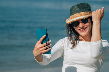 young woman with victory or success gesture with phone on the beach