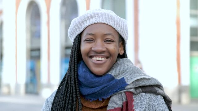 Portrait of young african woman with heterochromia looking at camera and smiling in winter.
