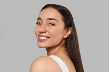 Portrait of beautiful young woman with elegant makeup on grey background