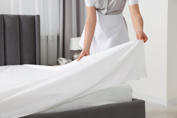 Maid making bed in hotel room, closeup - obrazy, fototapety, plakaty