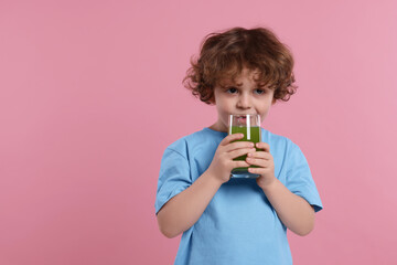 Cute little boy drinking fresh juice on pink background, space for text