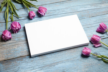 Blank white canvas mockup with flowers on blue wood. Rustic blue background with white canvas