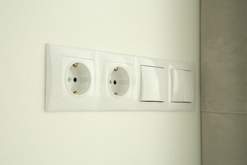 Light switches and power sockets on white wall indoors