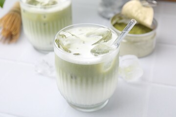 Obraz na płótnie Canvas Glasses of tasty iced matcha latte on white tiled table, closeup