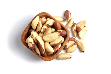 Brazil nuts in wooden bowl isolated on white. Peeled brazil nuts, top view