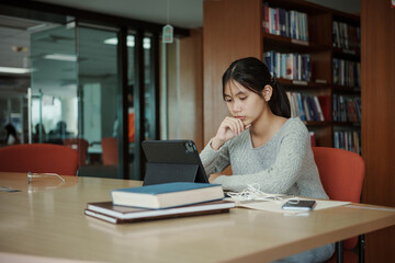 Asian student woman read books in library at university. Young girl stress tired have problem while study hard. Sadness concept