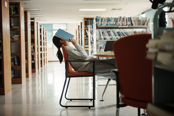 Asian student woman read books in library at university. Young girl stress tired have problem while...