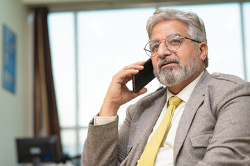 Senior businessman talking on smartphone at office.