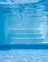 Underwater view white swimming pool steps with water reflection