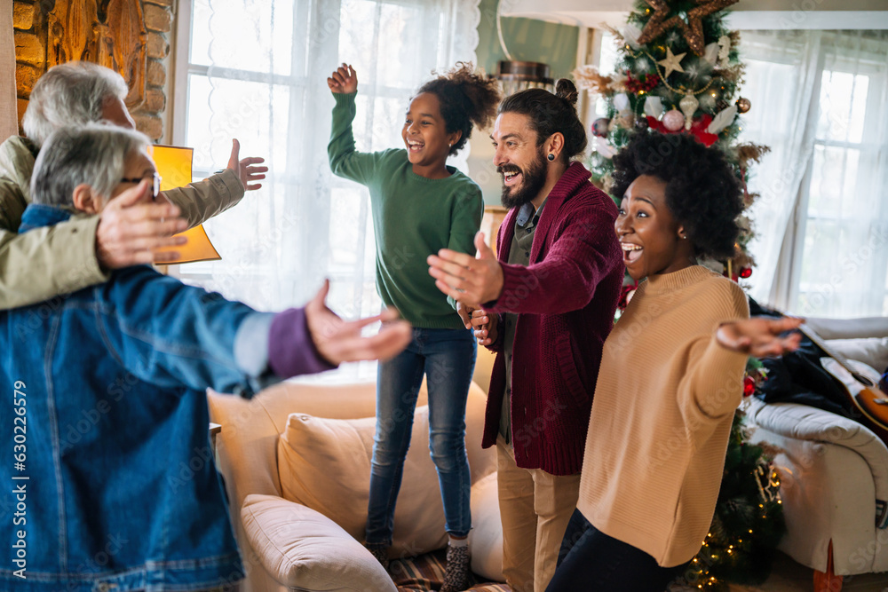 Wall mural Excited multiethnic family greeting grandparents on Christmas Day. Multi-generational happy family