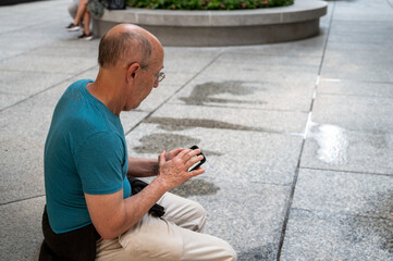 Active senior man checks cellphone on a new York City park bench