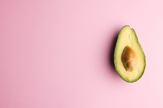 Close up of half of avocado and copy space on pink background