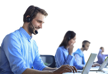 Smiling male call-center operator with headphones sitting at modern office with collegues on the backgroung, consulting online.