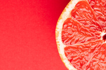 Close up of half of red grapefruit and copy space on red background