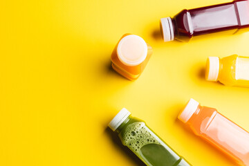 Close up of plastic bottles with fresh juice and copy space on yellow background