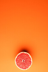 Close up of half of red grapefruit and copy space on orange background