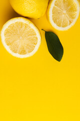 Close up of lemon, lemon slices and leaves with copy space on yellow background