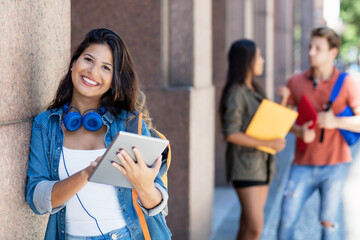 Lachende junge Studentin mit Tablet vor der Uni