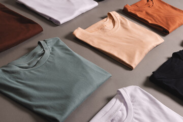 Multi coloured t shirts with copy space on grey floor background