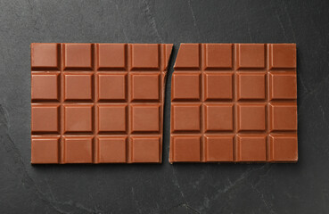 Tasty broken chocolate bar on grey table, top view
