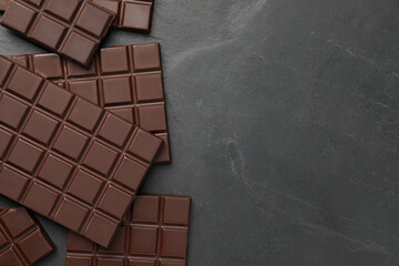 Pieces of tasty chocolate bars on grey table, flat lay. Space for text