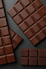 Pieces of tasty chocolate bars on grey table, flat lay