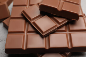 Delicious milk chocolate on light grey table, closeup