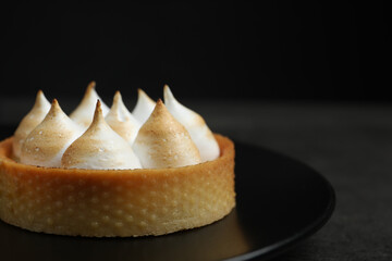 Tartlet with meringue on black table, closeup and space for text. Delicious dessert