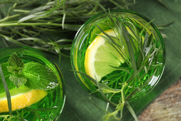 Glasses of refreshing tarragon drink with lemon slices on table, flat lay
