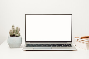 Laptop mockup with white screen and cactus with books and notepads. Laptop background for study and...