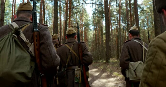 Squad Men Dressed As World War II Russian Soviet Red Army Soldiers Marching Through Spring Forest In Sunny day. Soldier Of WWII WW2 Times.