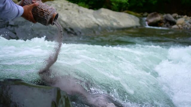 scattering the ashes into the water after cremation in a beautiful mountain river